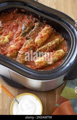 Cabbage rolls cooked in slowcooker with a bowl of sour cream Stock Photo