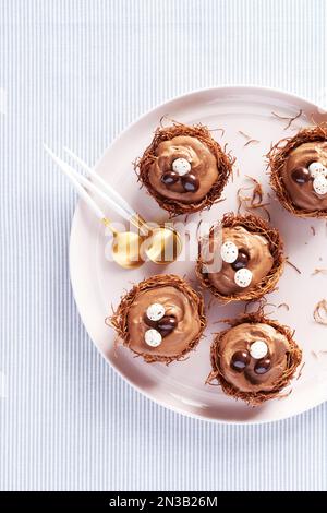 Plate of chocolate mousse nest cups with chocolate egg garnish and gold colored spoons Stock Photo
