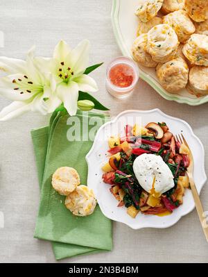 Poached egg on vegetables on fancy plate served with chedder herb scones Stock Photo