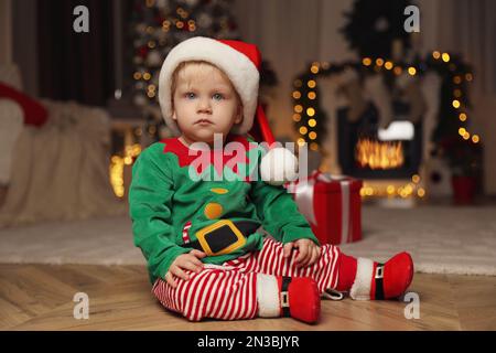 Cute baby in Santa's elf clothes at home. Christmas suit Stock Photo
