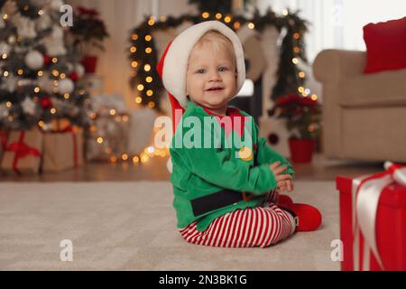 Cute baby in Santa's elf clothes at home. Christmas suit Stock Photo