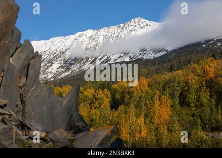 Jagged rock formations and fall colors on a sunny day with a blue sky along the Seward Highway outside of Anchorage, in contrast with the fresh sno... Stock Photo