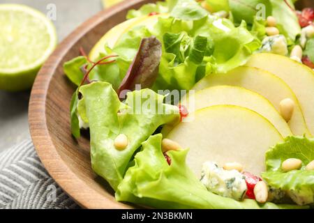 Fresh salad with pear slices in wooden bowl, closeup Stock Photo
