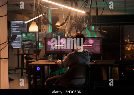 Professional spy breaking into computer system and hacking bank account, using virus to access online network. Hacker working with pc malware, committing internet fraud late at night. Stock Photo