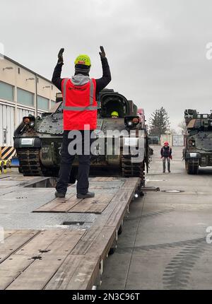 A contractor assigned to Army Field Support Battalion-Mannheim’s Coleman Army Prepositioned Stocks-2 worksite in Mannheim, Germany, ground guides an M2A2 Bradley infantry fighting vehicle onto a line haul transport truck to be delivered to a training area in support of Ukrainian forces tasked with learning how to operate and maintain Bradleys. (Photo by Jason Todd) Stock Photo