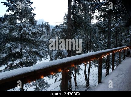 A crisp early morning after a freshly fallen snow covers a railing illuminated with a string of lights in the Mendenhall Valley at an inn near Juneau Stock Photo
