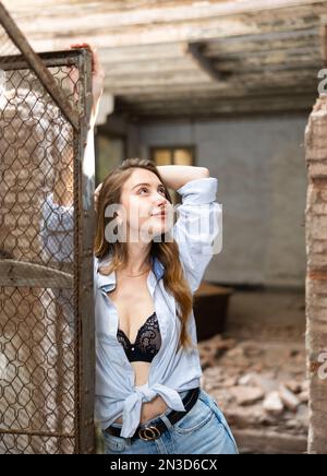 Woman in shirt tied in knot and black lace bra posing in abandoned house  Stock Photo - Alamy