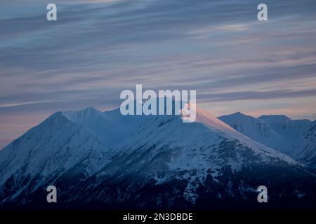 Sunset reflecting on the snow-covered mountaintop at Turnagain Arm; Anchorage, Alaska, United States of America Stock Photo