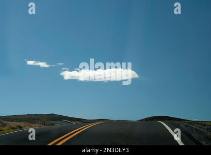 Cloud hovering over a quiet stretch of the Saddle Road, which crosses Hawai'i Island (Big Island) from Kona to Hilo Stock Photo