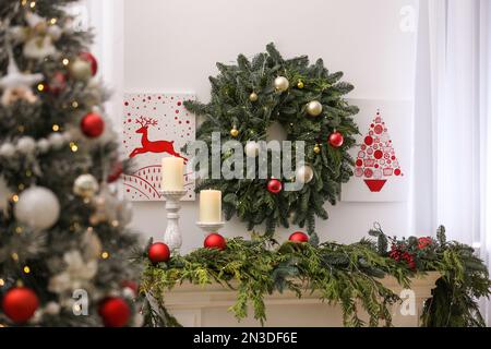 Beautiful Christmas pictures and wreath on wall in decorated room. Interior design Stock Photo