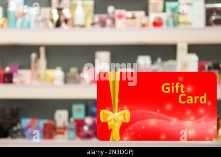 Store gift card. Blurred view of shelves with perfume bottles in shop Stock Photo