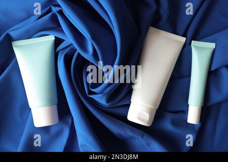 Set of luxury cosmetic products on blue fabric, flat lay Stock Photo