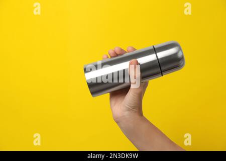 Woman holding modern thermos on yellow background, closeup Stock Photo