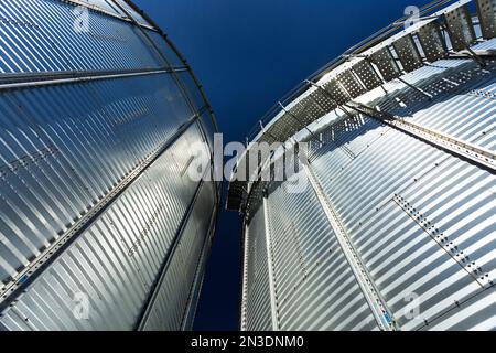 Close up and low angle of metal grain bins with blue sky; Southeast of Calgary, Alberta, Canada Stock Photo