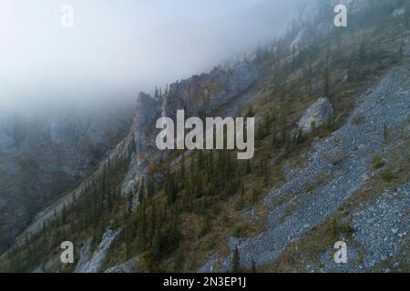 Aerial photos of a mountain side in the Ogilvie Mountains with misty clouds overhead. The mountains and landscape are like an artist palette as aut... Stock Photo