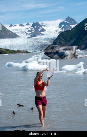 Woman emerges with an icy prize from the bracing waters of the lake at Grewingk Glacier in Kachemak Bay State Park, across from Homer Stock Photo