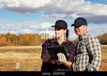A husband and wife using a portable wireless device to manage and monitor their Canola harvest; Alcomdale, Alberta, Canada Stock Photo