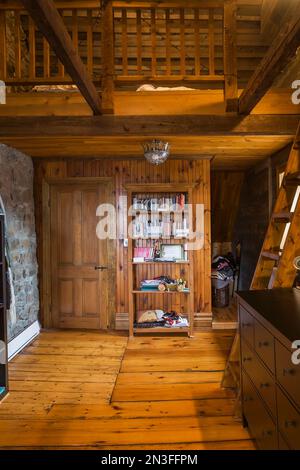 Attic bedroom with large pinewood floorboards, Miller's stairs and bed located on mezzanine inside old circa 1752 Canadiana style fieldstone house. Stock Photo