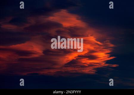 Very dramatic colourful clouds against a deep dark blue sky at sunset; Calgary, Alberta, Canada Stock Photo