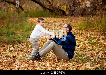 A father playing with his son during a family outing at a city park during the fall season; St. Albert, Alberta, Canada Stock Photo