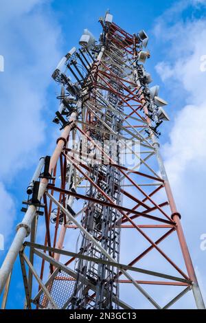 Telecommunication tower with blue and white clouds sky. Low angle view. Stock Photo