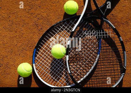 Tennis balls and rackets on clay court, flat lay Stock Photo