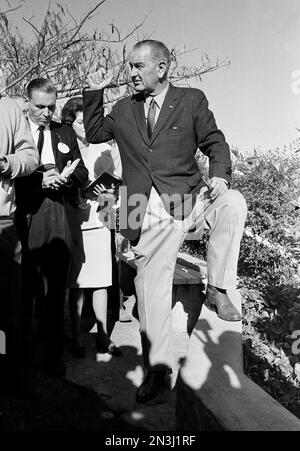 Wearing cowboy boots and khaki trousers President Johnson gestures as he explains to reporters the operation of the LBJ Ranch near Johnson City Texas Dec. 25 1963. A group of reporters and