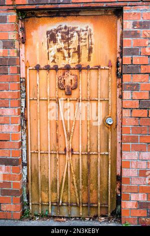 Old rusted metal exterior door and security gate attached to a brick wall on February 2, 2023 in New Orleans, LA, USA Stock Photo