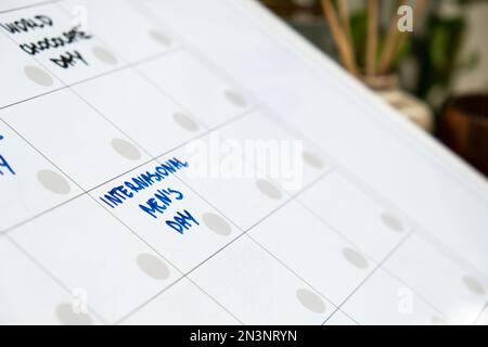 INTERNATIONAL MENS DAY on calendar to remind important event or holiday appointment Monthly PLANNER. Magnetic board with the days of the month. Place to enter important matters schedule. Concept for business planning. Whiteboard Planner magnetic monthly template. Interior of freelancer workplace  Stock Photo