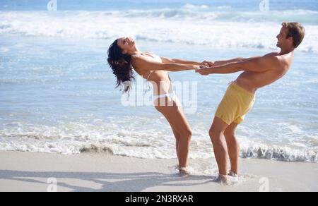 Hand-in-hand on the beach. A blissful couple frolicking on the beach together. Stock Photo