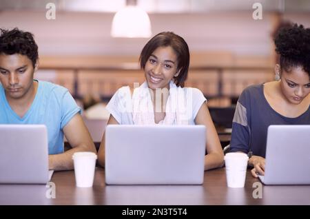 Working towards a bright future. A group of students using a laptop to complete a group assignment. Stock Photo