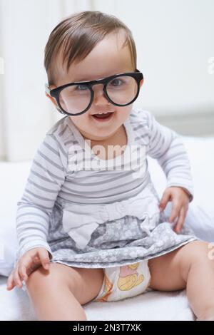 Shes destined for great things. A cute little baby girl wearing over-sized spectacles. Stock Photo