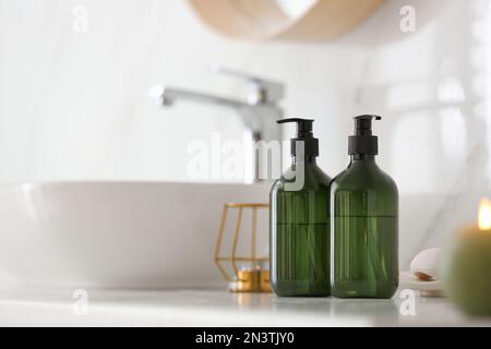 Green soap dispensers on countertop near sink in bathroom. Space for text Stock Photo