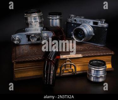 Still life with old cameras, lenses and negative film roll on old photo album Stock Photo