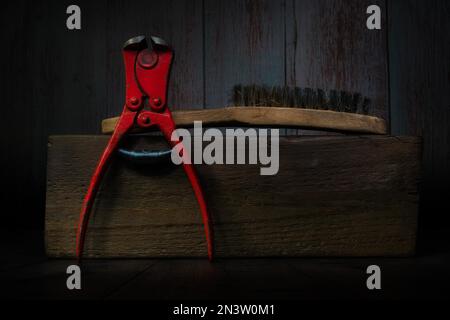 Still Life with Pliers and Wire Brush on Wooden Block Stock Photo
