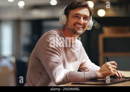 Happy graphic designer looking at the camera while sitting in a cafe. Male design professional working on a new project. Freelance designer working re Stock Photo