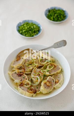 Swabian cuisine, Maultaschen in broth with stewed onions, soup plate, spoon, herbs, Germany Stock Photo