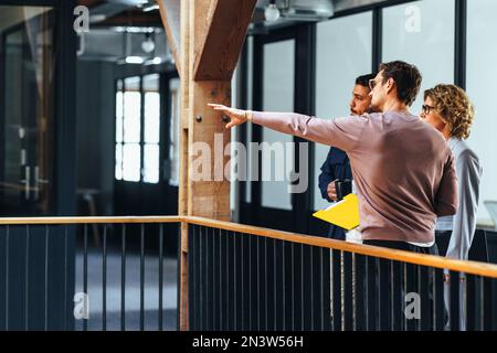 business people having a discussion with an interior designer on a balcony. business people planning a new project in their office; they consult with Stock Photo