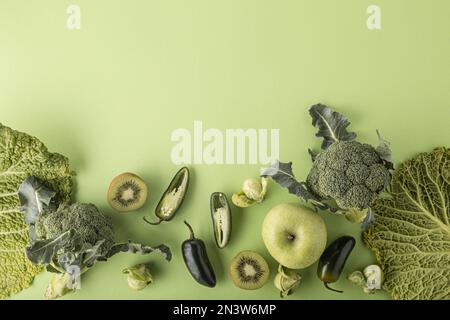 Creative layout food concept made of green fruit and vegetables on green background flat lay: avocado, kale, broccoli, Brussels sprouts, kiwi Stock Photo