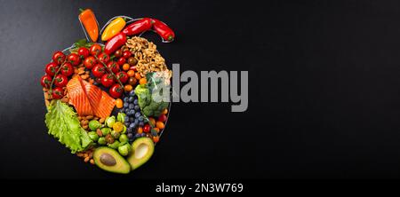 Healthy diet and nutrition for heart and cardiovascular system, healthy food, fruit and vegetables arrangement in realistic heart shape on black Stock Photo
