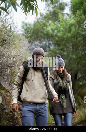 Seeking new adventure together. A young couple holding hands while walking through the forest. Stock Photo