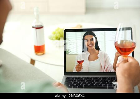 Friends drinking wine while communicating through online video conference at home. Social distancing during coronavirus pandemic Stock Photo