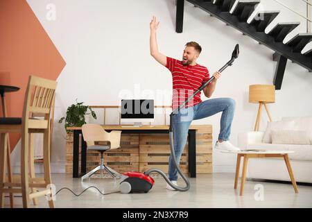 Young man having fun while vacuuming at home Stock Photo