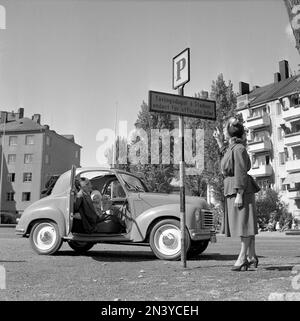 In the 1950s. A family with their car a Fiat convertible in a street in Råsunda Stockholm where the wife reads the sign. Sweden 1951 Conard ref 1711 Stock Photo
