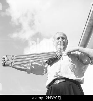 Strong man in the 1940s. A somewhat older man demonstrates that he has no trouble using and exercising his arm strenght and exercises with a chest expander. Sweden 1942  Kristoffersson ref H5-5 Stock Photo