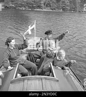 In the 1950s. A family in a sailingboat is seen waiving friendly to someone, as one does when being a boat owner. Sweden 1954 Kristoffersson ref BG19-8 Stock Photo