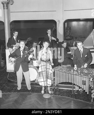 In the 1950s. A young woman seen singing on stage with a microphone in front of her at the dance establishment accompanied by an orchestra playing different musical instruments, guitar, violin, drums, piano and xylophone.  Stockholm Sweden 1954 Kristoffersson ref BP60-5 Stock Photo