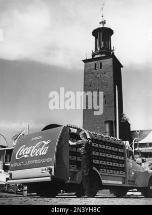 Coca cola in the 1950s. In 1 january 1953 Coca-Cola was first allowed to be manufactured and sold in Sweden, previously being restricted from sales in Sweden since the content of Coca-cola included forbidden substances like phosphoric acid and caffeine. One of the first  distribution trucks of the brewery Mineralvattenfabriken Tre Kronor loaded with Coca-Cola bottles pictured in Stockholm with the town hall in the background. Volvo trucks model L34 modifyed and painted in red for the exclusive use on Coca-Cola trucks. Coca-Cola was early with having advertising on their vehicles. Sweden 1953 Stock Photo