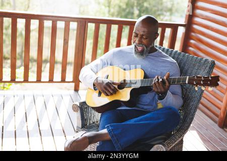 Man sitting on a chair and singing and playing an acoustic guitar ...