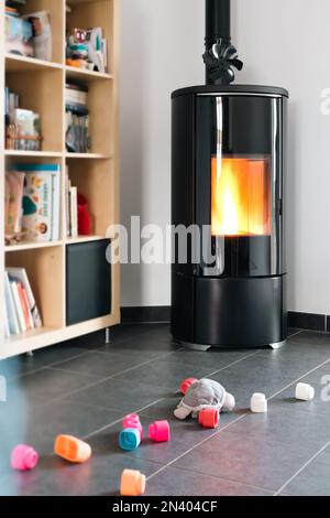 Pellet stove with some toys in front, with flames and library Stock Photo